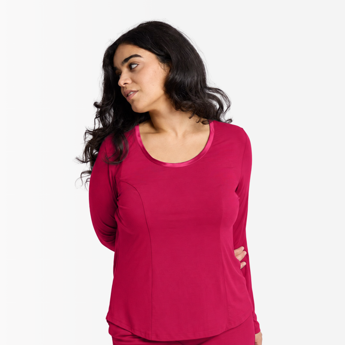 A woman modeling a long-sleeve scoop-neck Princess Seamed top with a satin trim neckline in Sunset Pink photographed against a clean white studio background.