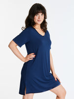 A woman wearing a short-sleeved, scoop-neck, knee-length nightie in a solid color, with satin trim detailing.