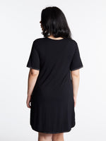 A woman wearing a short-sleeved, scoop-neck, knee-length nightie in a solid color, with satin trim detailing.