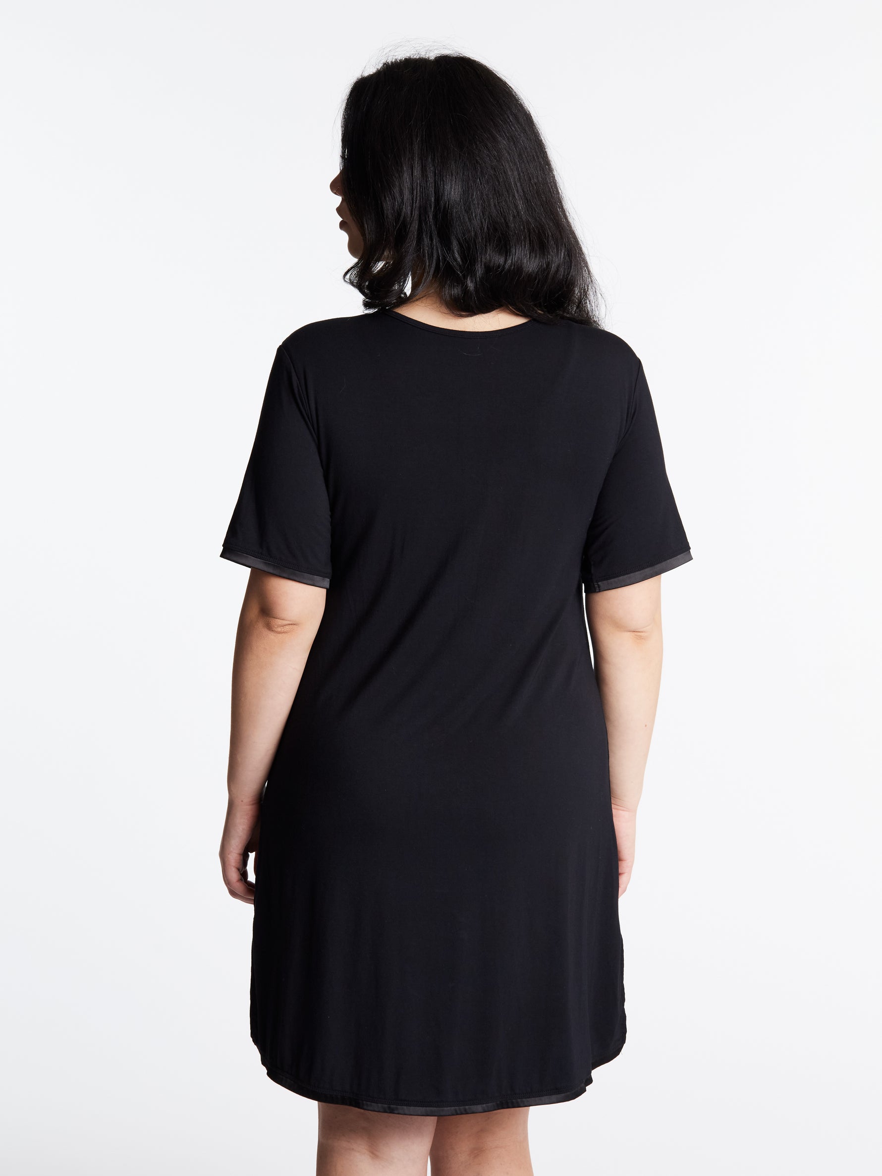 A woman wearing a short-sleeved, scoop-neck, knee-length nightie in a solid color, with satin trim detailing.