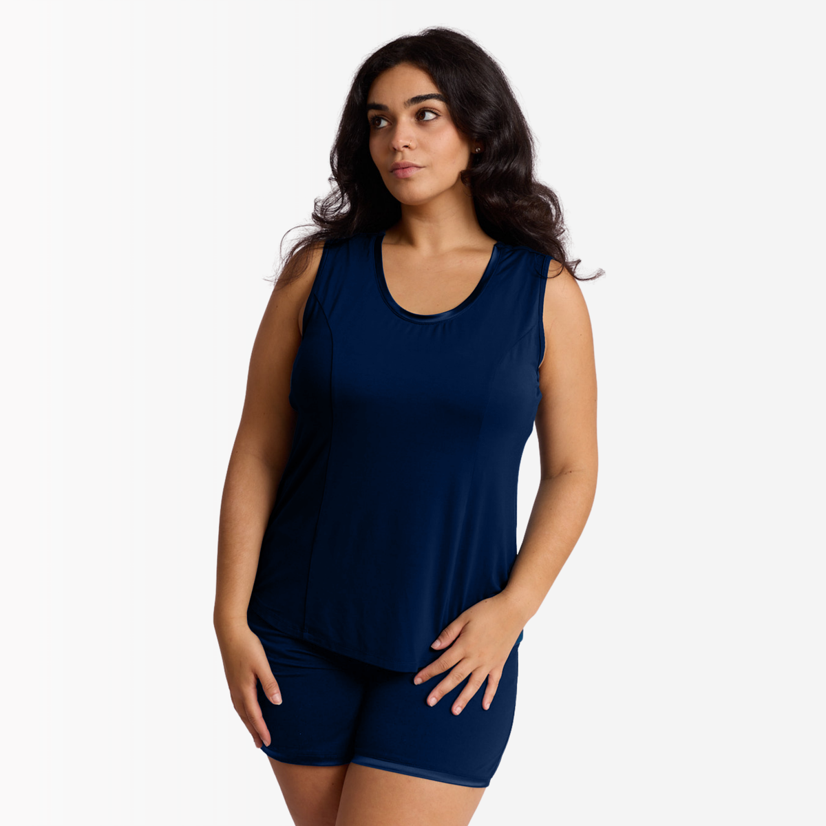 A woman modeling a matching Blue tank top and shorts sleep set against a plain white studio background. color night sky