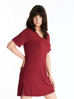 A woman wearing a short-sleeved, scoop-neck, knee-length nightie in a solid color, with satin trim detailing.