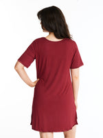 A woman wearing a short-sleeved, scoop-neck, knee-length nightie in a solid color, with satin trim detailing.